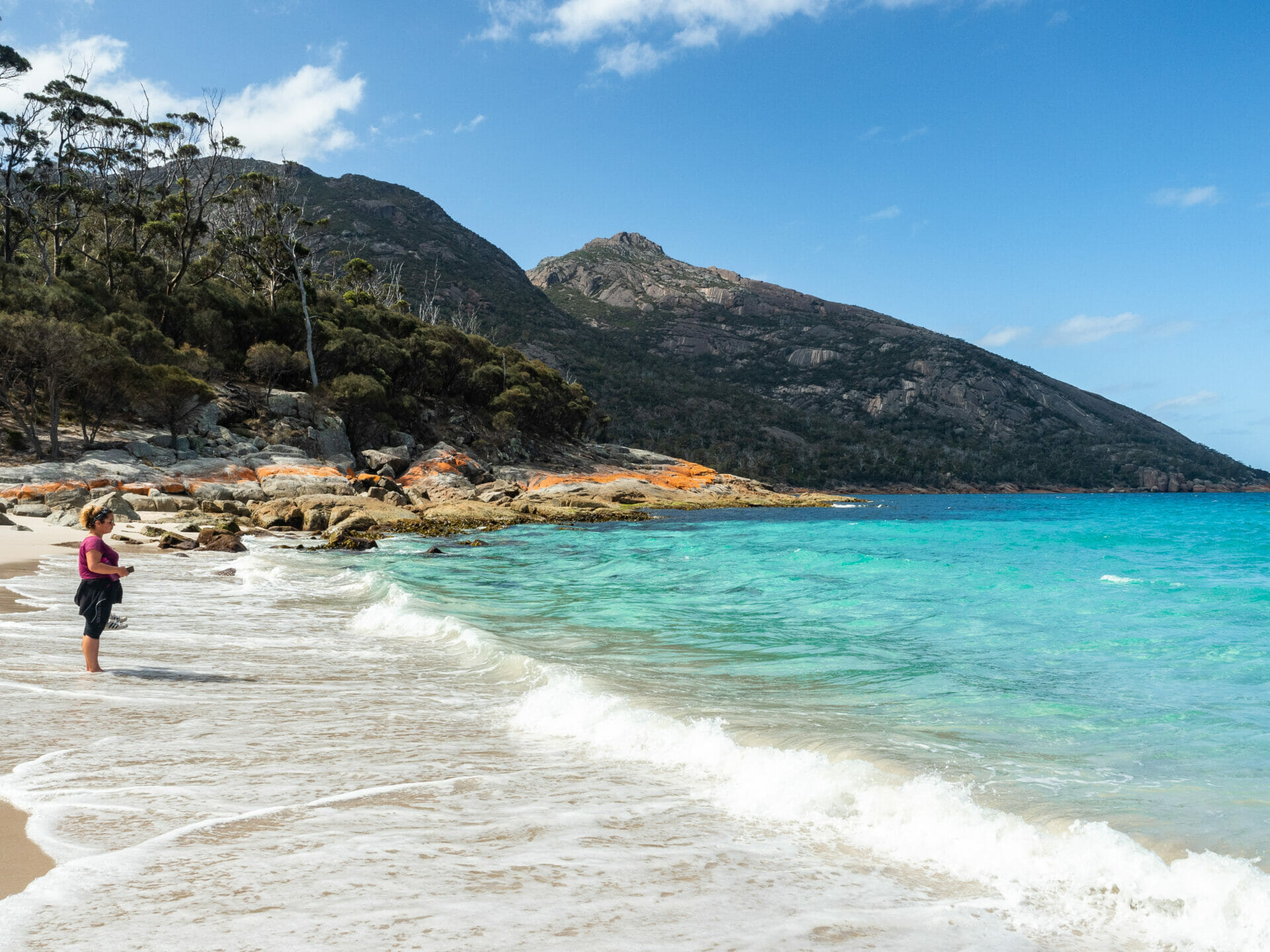 A family relaxing on the pristine white sands of Wineglass Bay beach, surrounded by the natural beauty of the Freycinet Peninsula.