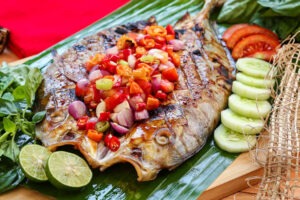 Ikan bakar sambal pedas yang disajikan dengan warna kecokelatan dan sambal merah di atasnya, siap disantap dengan nasi hangat